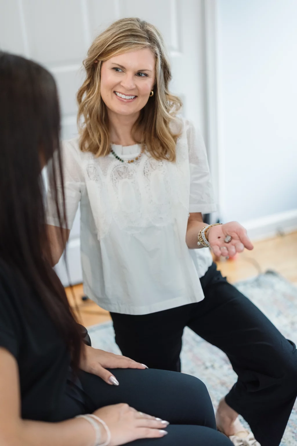 Headshots and branding for Davis Audiology in Taylors SC.: Smiling woman in a white blouse gestures while speaking with another woman seated in the foreground.