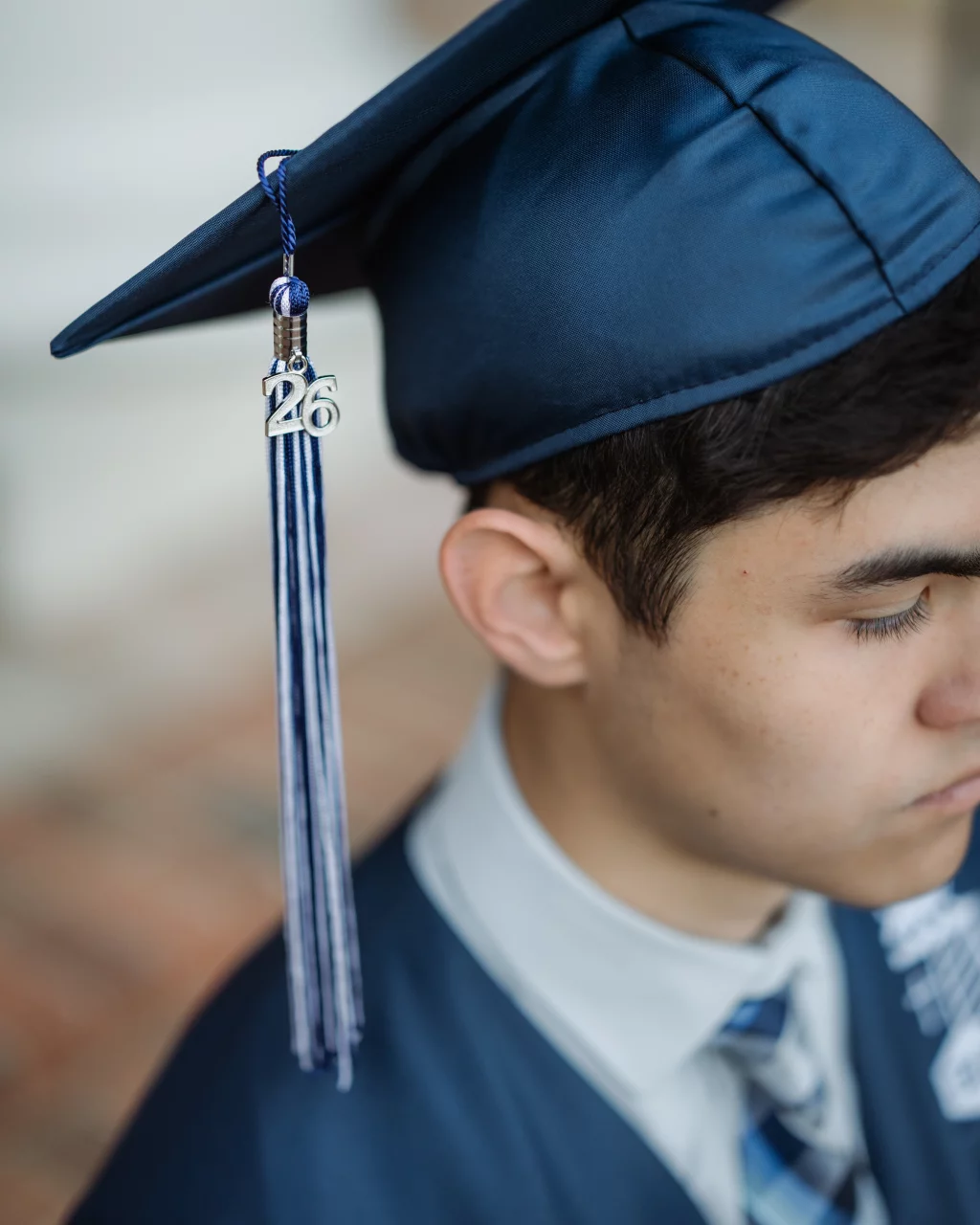 Jared's senior photos taken at Furman University: Close-up of a person wearing a blue graduation cap and gown, with a tassel featuring the number "26".