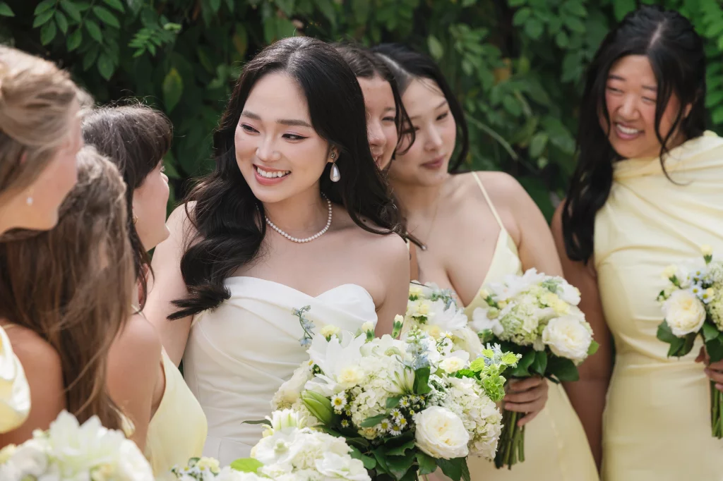 Robbie & Hannah's Wedding @ Edinburgh West, Taylors SC: Smiling bride in a strapless white gown surrounded by bridesmaids in pale yellow dresses, holding white floral bouquets.