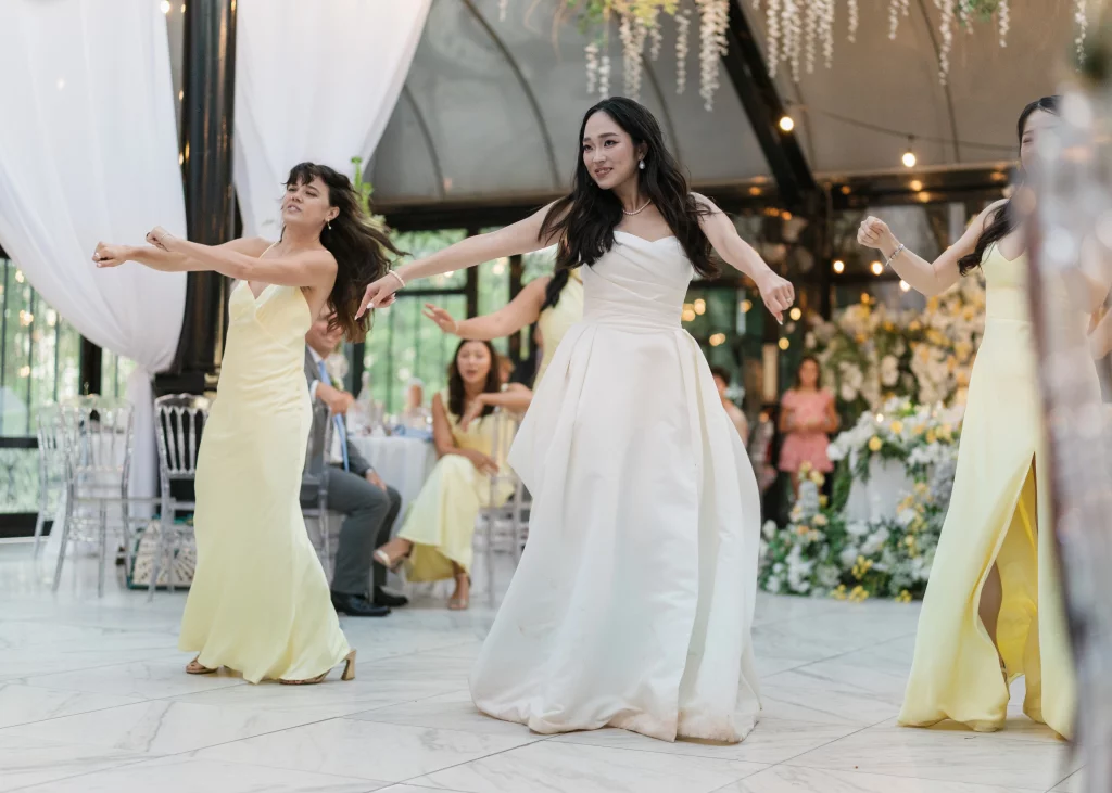 Robbie & Hannah's Wedding @ Edinburgh West, Taylors SC: Bride and bridesmaids dance at a wedding reception beneath floral decorations.