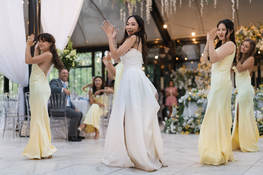 Robbie & Hannah's Wedding @ Edinburgh West, Taylors SC: Bride and bridesmaids dance during a wedding reception, surrounded by floral decorations and seated guests.