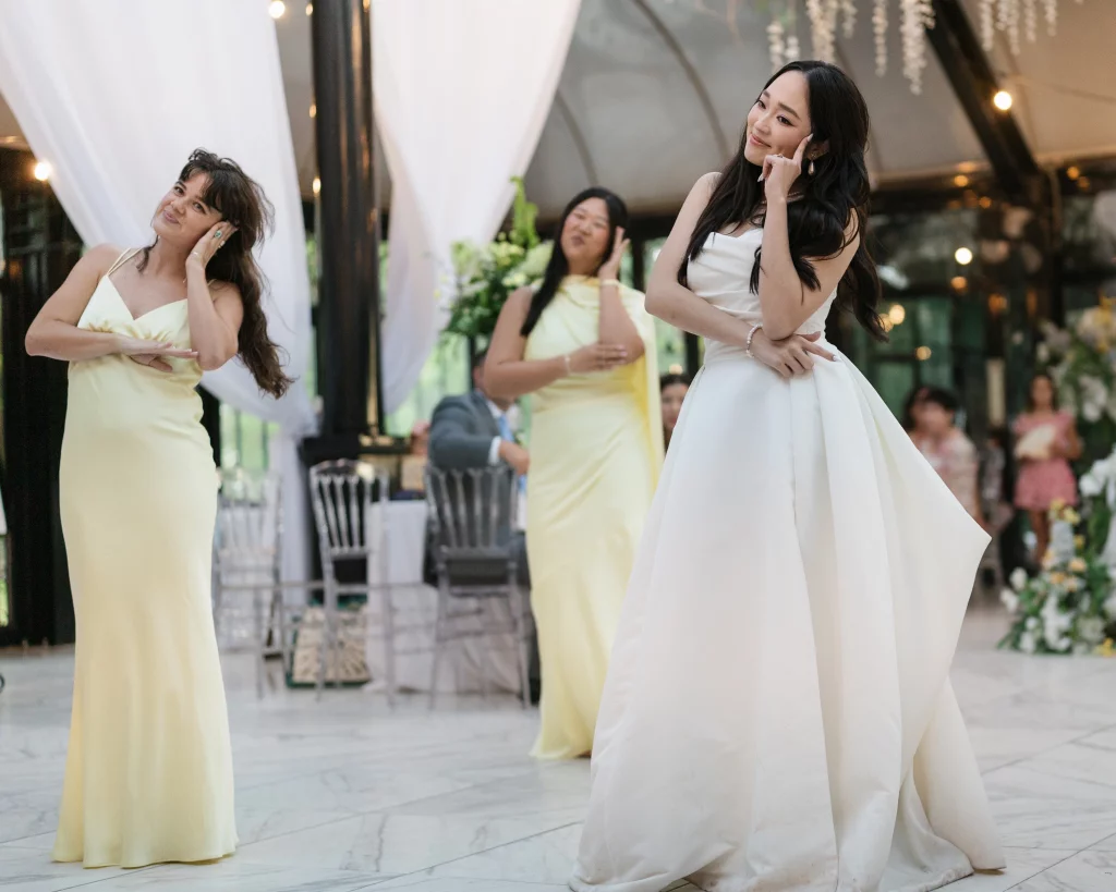 Robbie & Hannah's Wedding @ Edinburgh West, Taylors SC: Bride in a white gown poses with two bridesmaids in pale yellow dresses at a decorated wedding reception.
