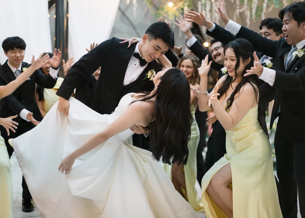 Robbie & Hannah's Wedding @ Edinburgh West, Taylors SC: Newlywed couple dance playfully as wedding guests cheer around them.
