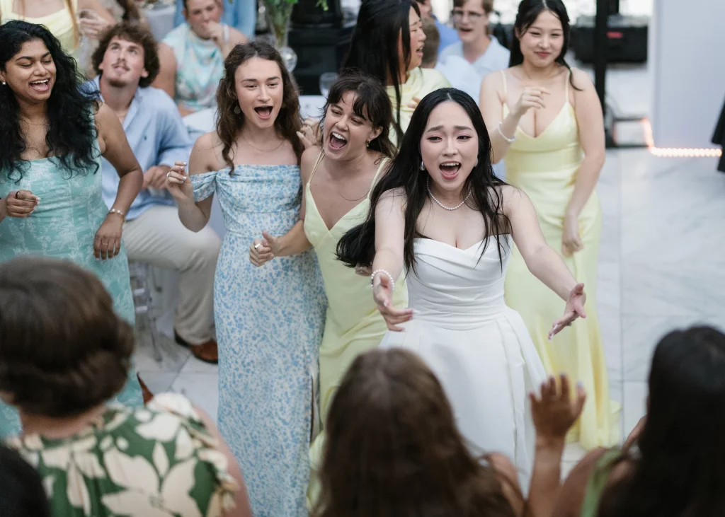 Robbie & Hannah's Wedding @ Edinburgh West, Taylors SC: Bride in a white dress dances with cheering guests at a wedding reception.