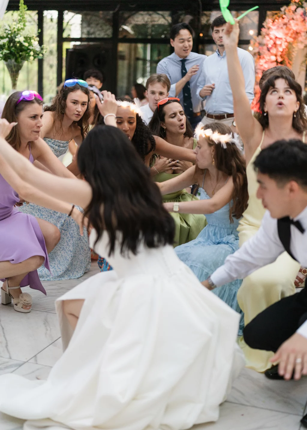 Robbie & Hannah's Wedding @ Edinburgh West, Taylors SC: Bride and wedding guests dance energetically indoors, with guests wearing colorful dresses and novelty sunglasses.