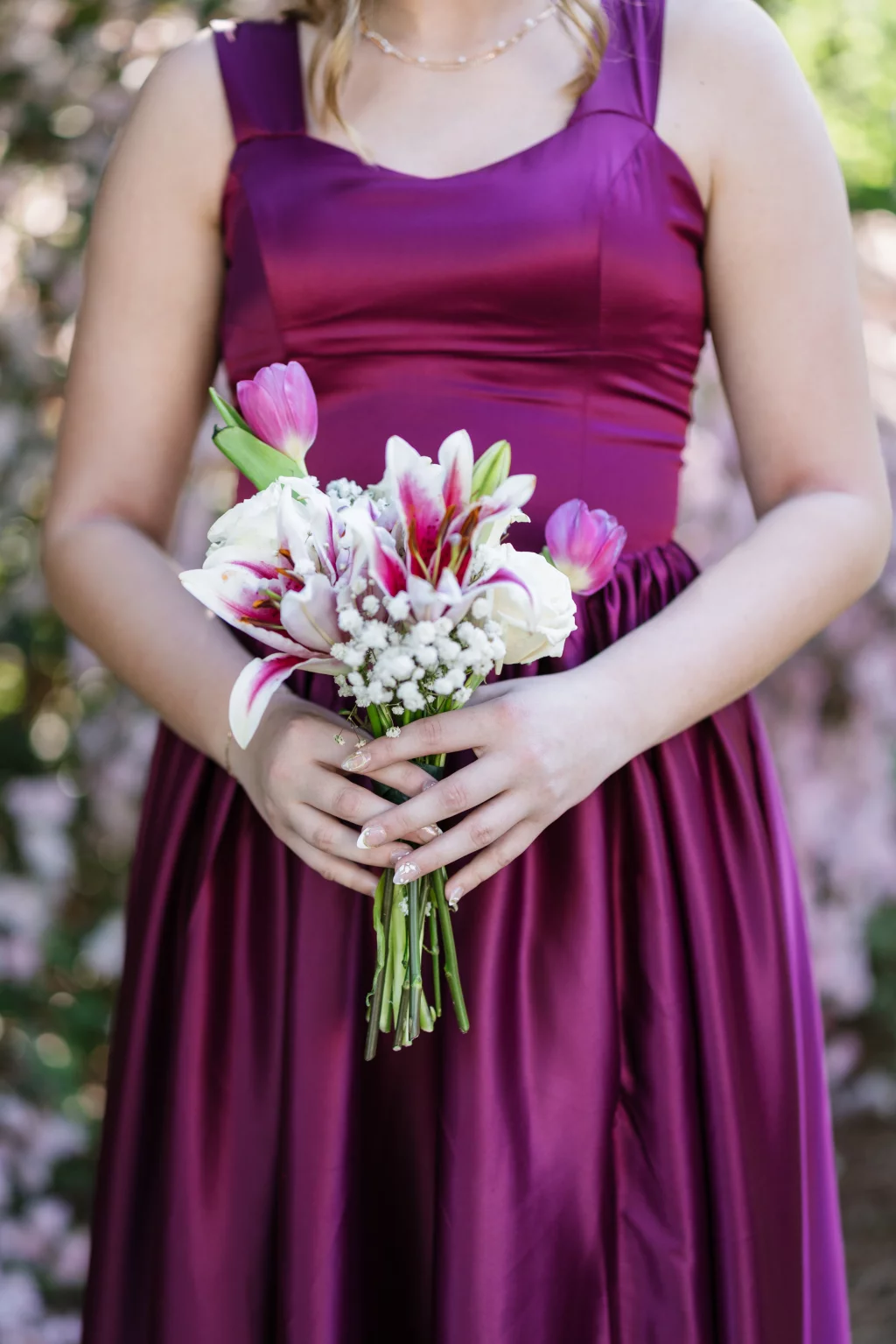 BJA Jr/Sr Banquet Prom at Sue Simpson Park: Person in a sleeveless magenta dress holding a bouquet of pink and white flowers with greenery.