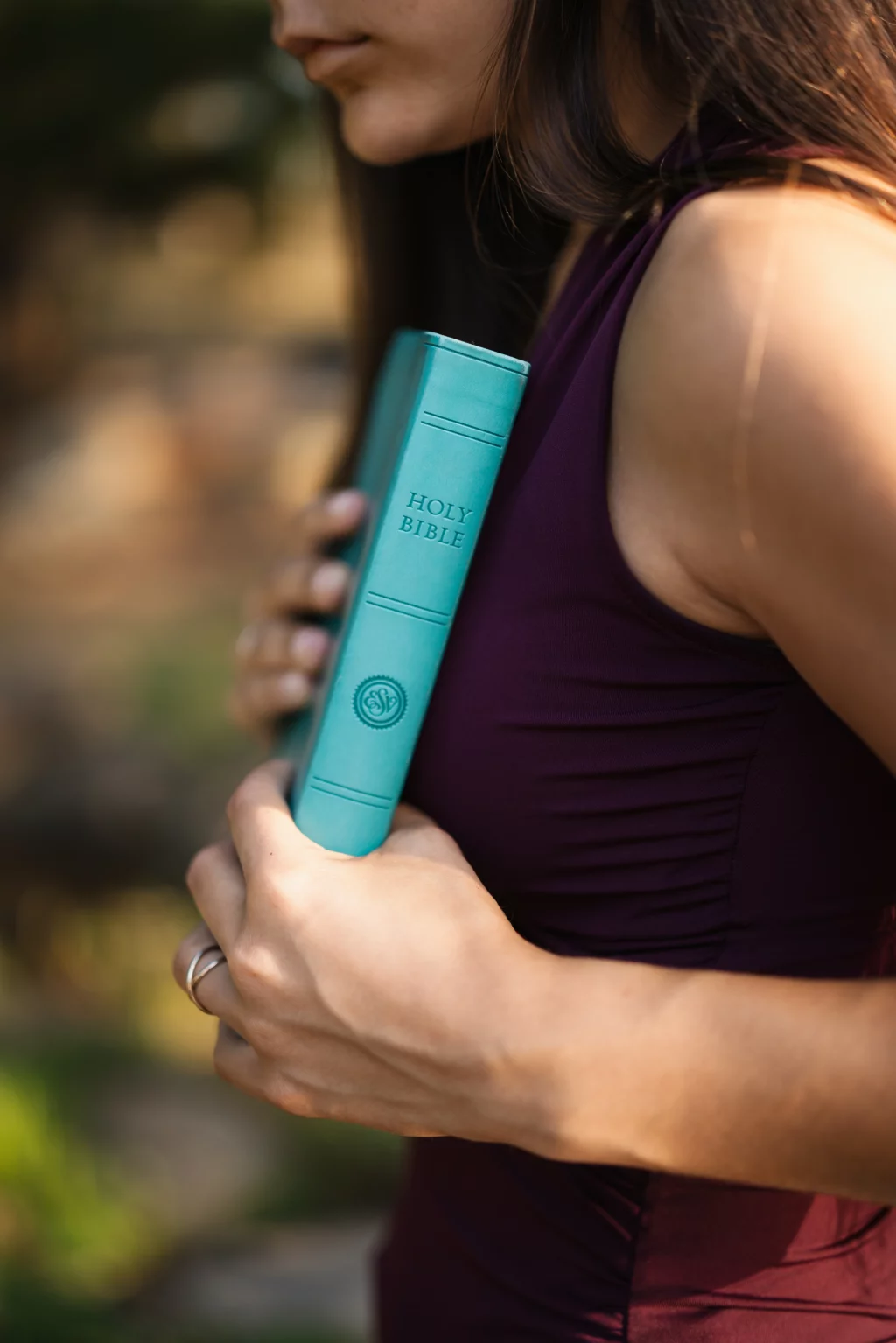 Olivia's senior photos taken at Furman University: A woman in a sleeveless purple top holds a teal Holy Bible close to her chest.