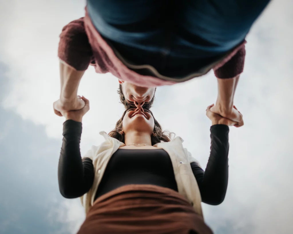 Ethan & Savanah's couple photo session taken at Campbell's Covered Bride, Greenville County: Low-angle shot of a couple holding hands and touching noses against a cloudy sky.