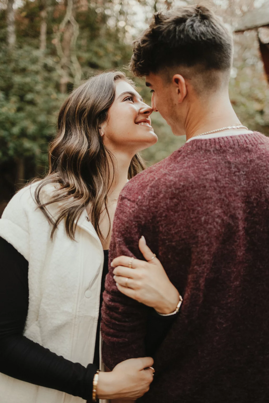 Ethan & Savanah's couple photo session taken at Campbell's Covered Bride, Greenville County: Couple embracing outdoors, woman smiling up at man, blurred greenery background.