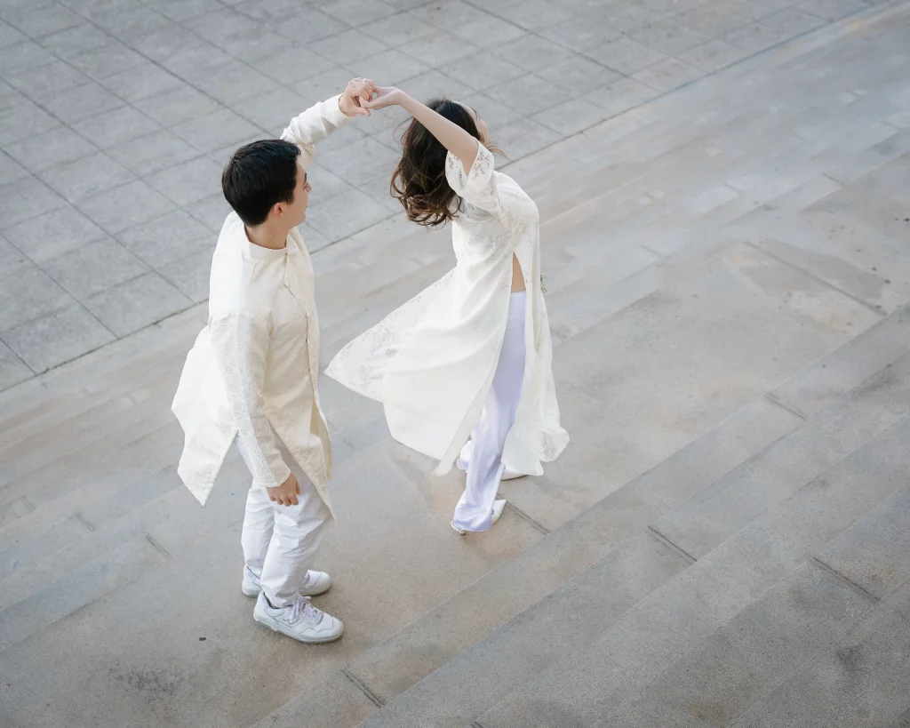 Robby and Hannah's couple photo session taken Downtown, Greenville: Couple dressed in traditional white attire dancing on outdoor stone steps, man twirling woman.