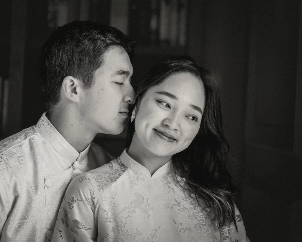 Robby and Hannah's couple photo session taken Downtown, Greenville: Black and white close-up photo of a couple in traditional clothing, with the man gently leaning in toward the woman who is smiling and looking slightly to the side.