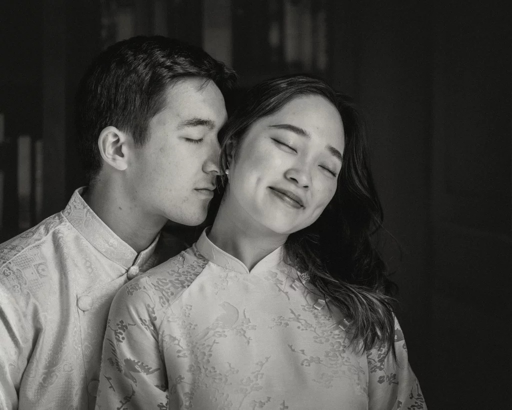 Robby and Hannah's couple photo session taken Downtown, Greenville: Black and white photo of a couple with eyes closed, the man gently resting his face near the woman's ear, both wearing traditional patterned clothing.