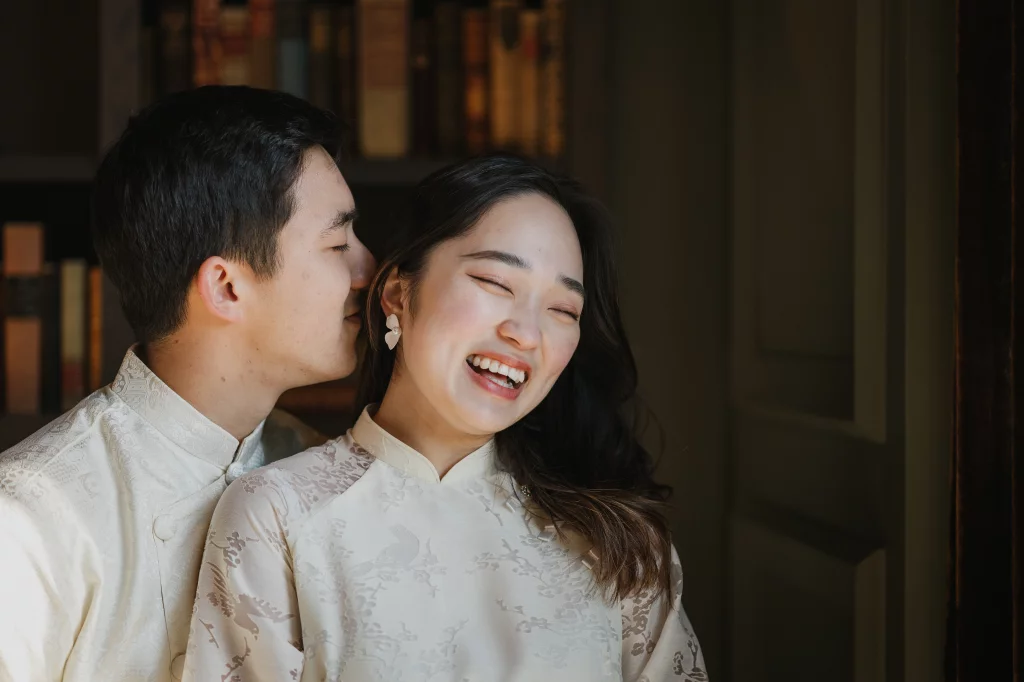 Robby and Hannah's couple photo session taken Downtown, Greenville: Couple in traditional attire sharing an intimate moment, with the man gently kissing the woman's cheek as she laughs joyfully.