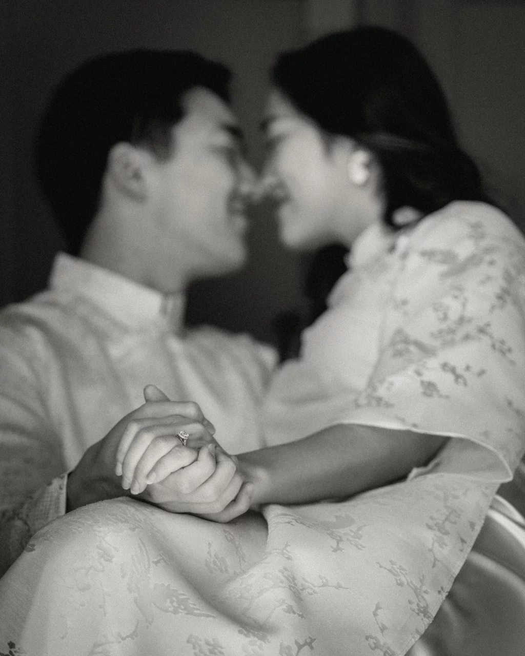 Robby and Hannah's couple photo session taken Downtown, Greenville: Black and white photo of a couple holding hands closely, with the focus on an engagement ring as they lean in towards each other, their faces softly blurred.