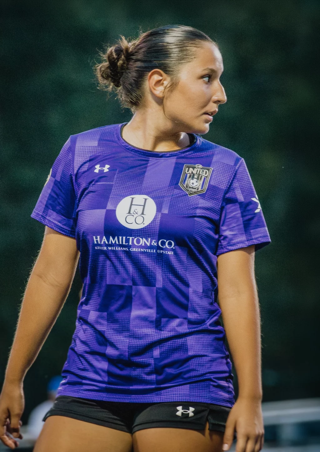 United FC - Furman Region -: A female soccer player in a purple jersey with "Hamilton & Co." and "United" logo stands outdoors, looking to her right.